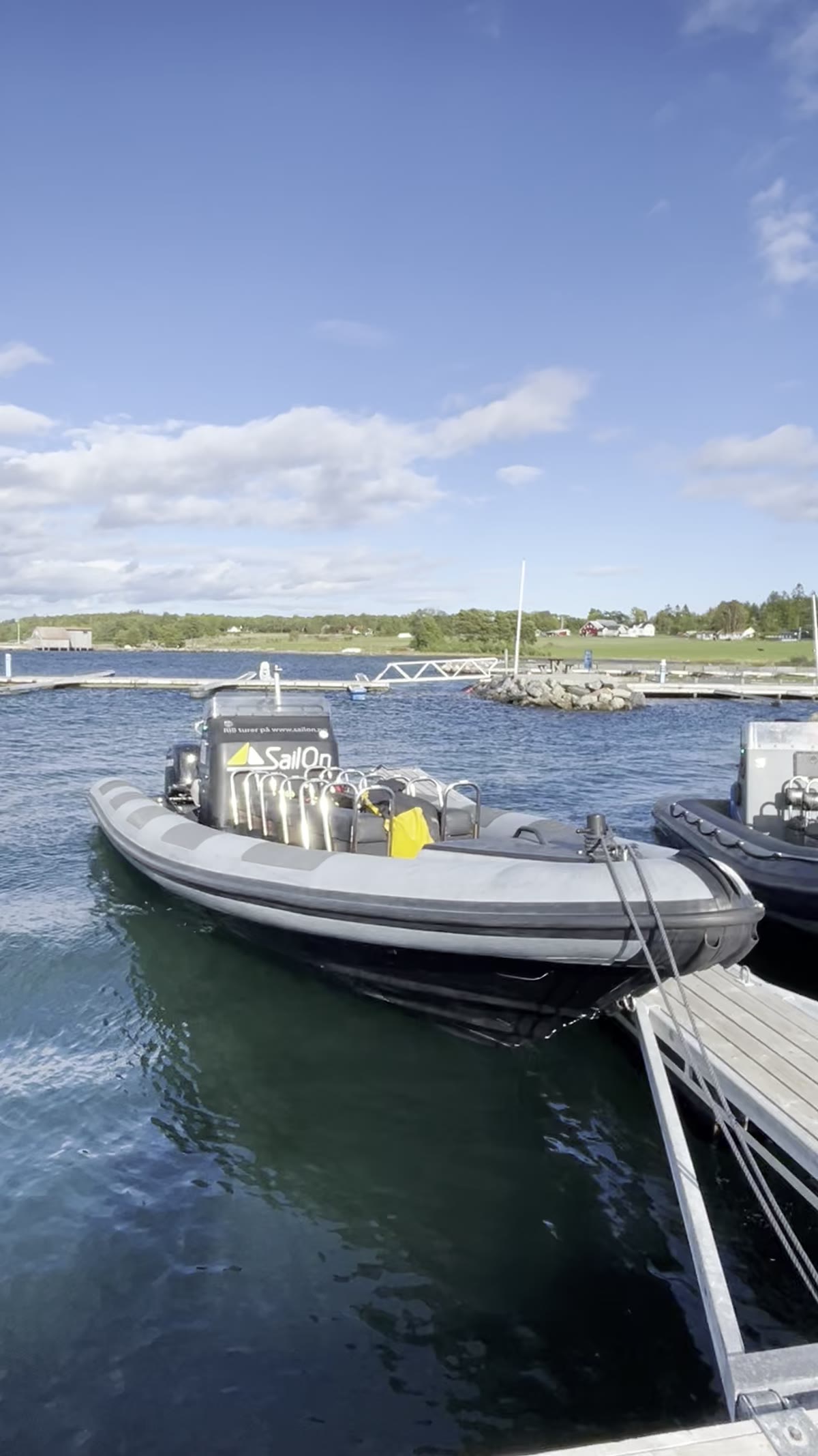 To RIB-er fortøyd ved en brygge, grønne øyer bak